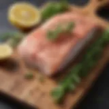 Fresh basa fillet on a wooden cutting board with herbs