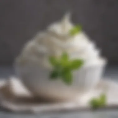 A close-up of a bowl filled with fluffy whipped cream garnished with mint leaves.